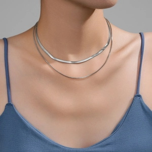 Close-up of a silver layered necklace featuring a herringbone and box chain on a model