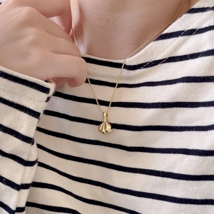 Macro shot of 925 silver golden garlic pendant necklace worn on a striped shirt