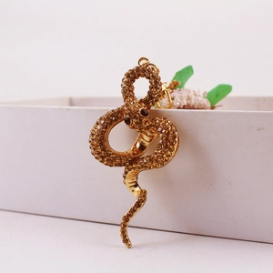 Creative golden snake keychain with brown rhinestones displayed on a white box