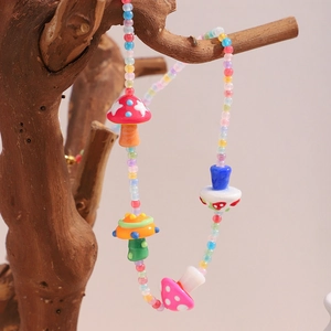 Détail d'un collier de perles colorées avec pendentifs champignons sur une branche