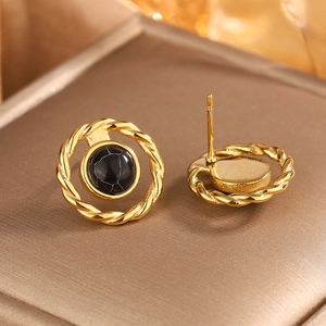 Macro shot of vintage gold twist earrings with black marble stone on luxury leather box