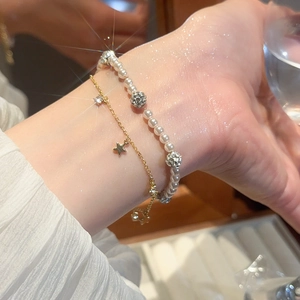 Close-up of double-layer bracelet with white pearls, zircon stars and gold chain