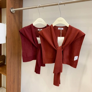 Detailed close-up of knitted wool shawls in dark red and brick red with tie-front design