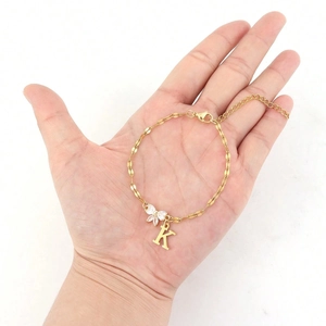 Detail of golden bracelet with K-letter pendant and rhinestone bow on hand