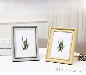 Detail of Nordic ivory photo frames in light grey and wood with botanical art prints