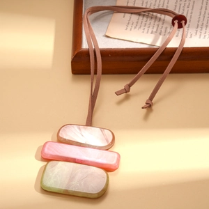 Detail of candy-colored acrylic geometric pendants on a brown suede sweater chain cord