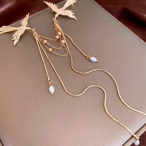 Detailed view of golden phoenix brooch with faux pearl tassels on champagne velvet