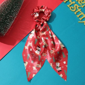 Detail of red silk Christmas scrunchie with reindeer pattern and long ribbon streamers