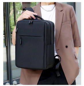 Business commuter backpack in black nylon held by handle showing its professional size