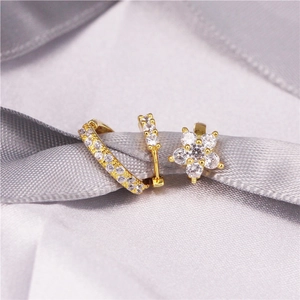 Detailed macro view of gold-tone star and flower earrings set with clear zircon stones