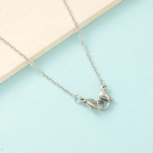 Detail of silver stainless steel box chain with dual lobster clasps on stone background