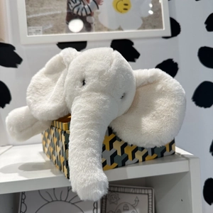 Close-up of a soft white plush elephant toy with long ears in a decorative setting