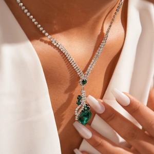 Détail du collier argenté à deux rangs avec pendentifs cœur vert et émeraudes