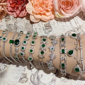 Elegant emerald green gemstone bracelets in silver settings shown on a female wrist