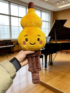 Close-up of a cartoon gourd flute plush toy with a cute smile in a piano room setting