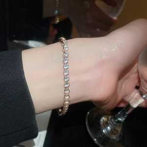 Close-up of sparkling 18k tennis bracelet with round gemstones on a woman's wrist