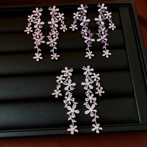 Close-up of zircon flower tassel earrings in pink, purple and white variants