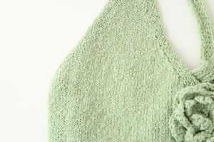Detail of mint green knit dress showing intricate crochet texture and floral embroidery