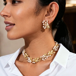 Close-up of vintage gold leaf and pearl necklace set worn by a model for weddings