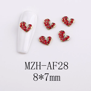 Detailed view of red rhinestone heart nail charms with gold metal base on white tips
