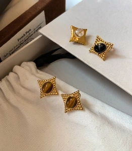 Détail de boucles d'oreilles vintage œil de tigre avec bordure dorée perlée sur tissu