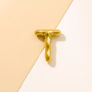 Macro shot of a chunky gold T-letter pendant with a glossy balloon metal texture