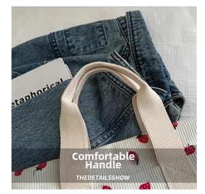 Detail showing high-quality stitching on white corduroy strawberry tote bag handles