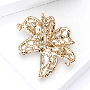 Detailed view of an elegant gold hollowed-out butterfly brooch with intricate metal design