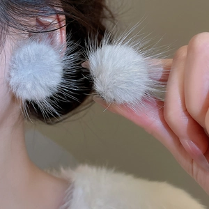 Gros plan sur des boucles d'oreilles boules en résine grise avec tiges en argent fin
