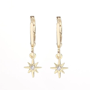 Macro detail of gold star drop earrings with sparkling center zircon stones