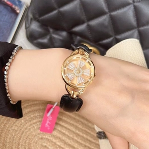 Detail of rose gold wristwatch with floral dial and black leather strap on model's wrist