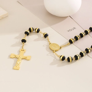 Macro shot of 18K gold-plated cross pendant and black beads on religious rosary necklace