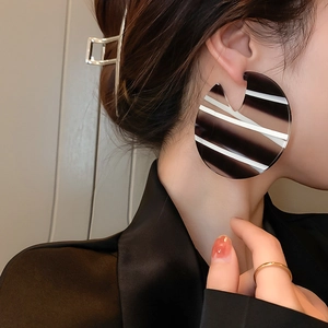 Fashionable large striped acrylic hoop earrings shown on a model with geometric pattern