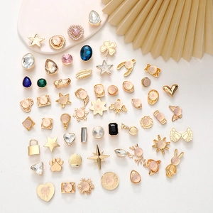 Close-up of gold metal charms with colorful gemstones and pearls for DIY jewelry and shoes