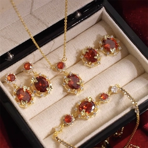 Detailed jewelry set with red oval stones and golden butterfly accents in luxury gift box