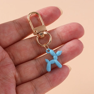 Detailed view of light blue balloon dog keychain with golden clasp on hand