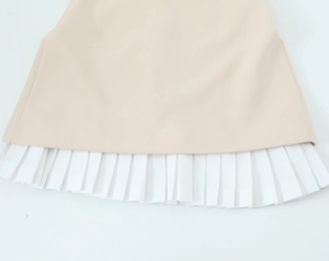 Détail de la robe sans manches abricot avec ourlet blanc plissé et texture tissée fine