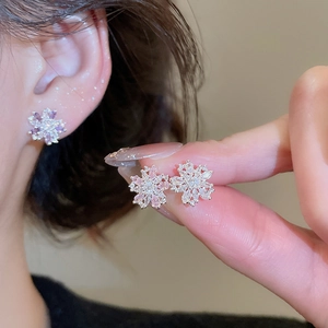 Macro detail of snowflake stud earrings with pink zircon stones and silver finish