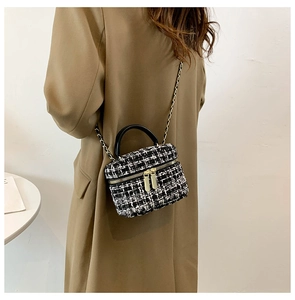 Model met een zwart-witte tweed emmerstas met ketting bij een stijlvolle kaki jas