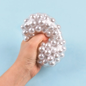 Close-up of hand squeezing transparent stress ball filled with white pearly beads
