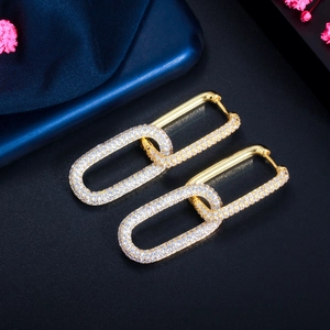 Close-up of gold chain-link earrings with micro-paved white zircons on a black base