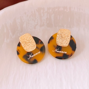 Detail of gold-plated earrings with tortoiseshell resin and Nuance engraving
