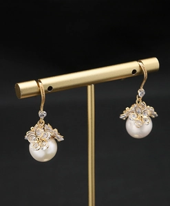 Detail of baroque pearl drop earrings with golden floral zircon studs on display