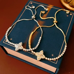 Close-up of gold and silver clover bracelets with sparkling zircons on jewelry box