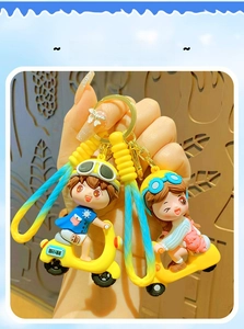 Detail of cartoon couple on yellow scooters keychains with woven lanyards held by hand