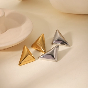 Detailed view of polished 3D triangle earrings in gold and silver finish on a soft background