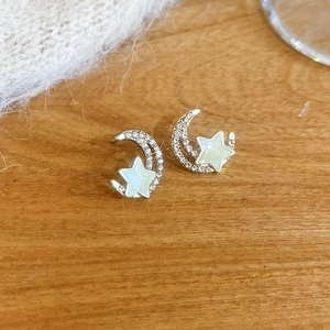 Macro view of gold star and crescent moon stud earrings with glittering crystals