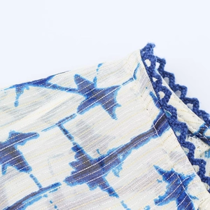 Dettaglio del tessuto in cotone e lino con stampe di stelle blu e bordo all'uncinetto