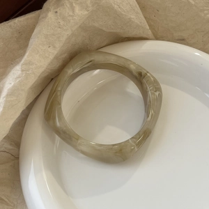 Detail view of square marble resin bangle with smooth edges on minimalist display