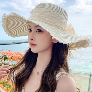 Close-up of summer straw sun hat with delicate lace, pearls and wide brim detail